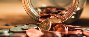 A jar with coins spilling onto a table