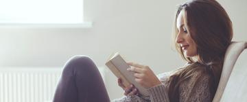 A woman reading a book on the couch.